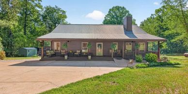 Rustic house with a large porch and metal roof.