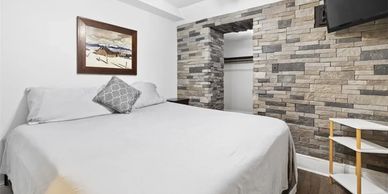 Cozy bedroom with stone accent wall and simple decor.