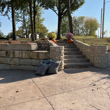Stone steps with pumpkins and flowers leading to a grassy area.