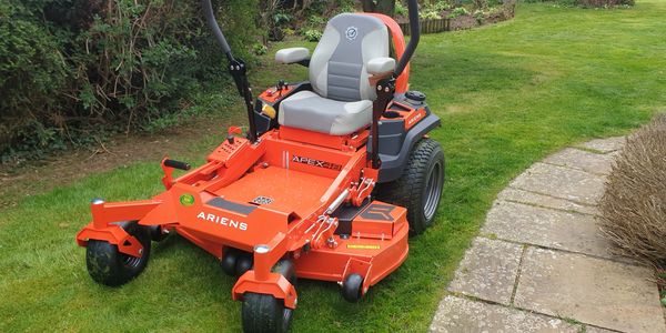 Orange Ariens Apex 48 zero-turn lawn mower on green grass.