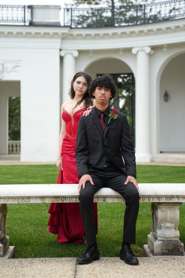 Young couple dressed elegantly for a formal event in front of a classical building.