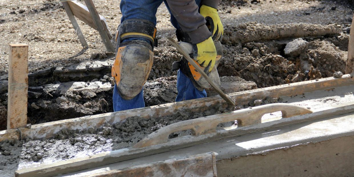 Construction worker smoothing wet concrete on a construction site.
