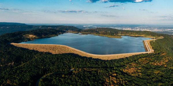 A large reservoir surrounded by green hills and a clear sky.