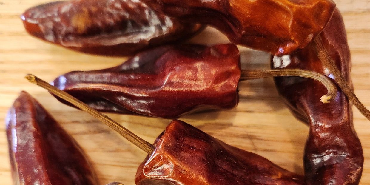 Close-up of dried red chili peppers on a wooden surface.