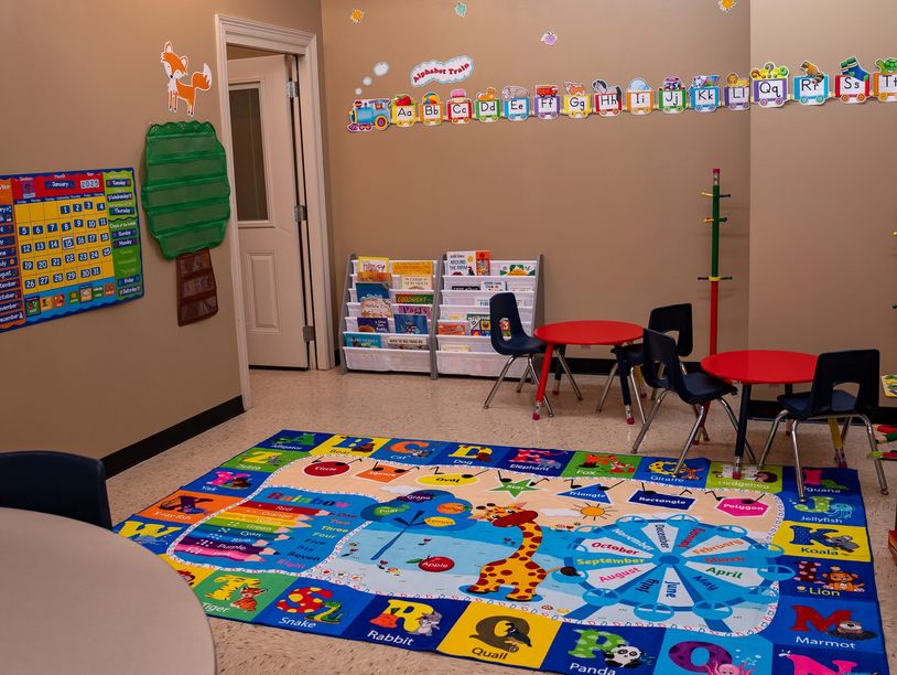Colorful preschool classroom with educational rugs and child-sized furniture.