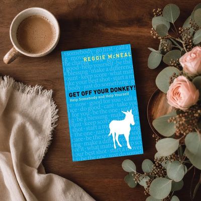 Book titled 'Get Off Your Donkey!' by Reggie McNeal with coffee and flowers nearby.