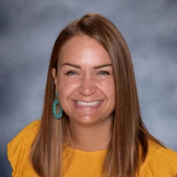 Smiling woman with long brown hair in yellow top.
