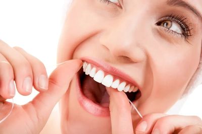 Woman brushing teeth and smiling to demonstrate proper dental hygiene