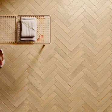 Light wood herringbone floor with a woven bench and folded towel.