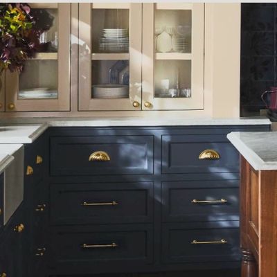 Elegant kitchen with navy blue cabinets, brass handles, and marble countertops.