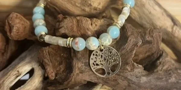 Beaded bracelet with a tree of life pendant on driftwood.