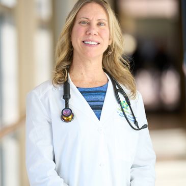 Smiling female doctor in white coat with stethoscope.