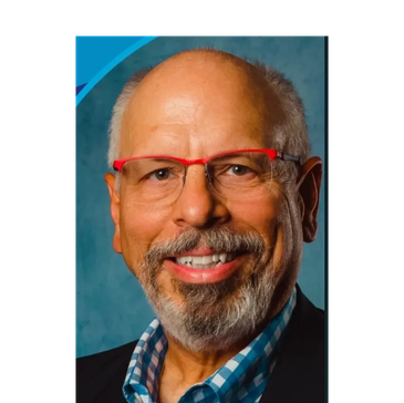 Smiling older man with red glasses and beard.