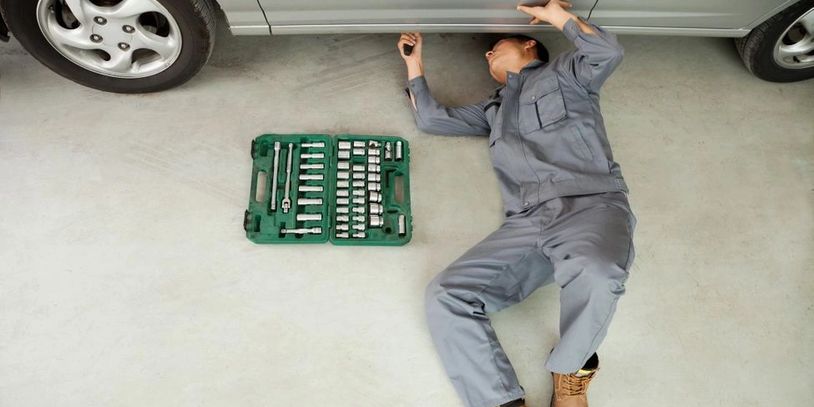 View of a man repairing the car lying on the floor
