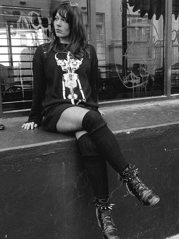 Woman in skeleton sweater sitting outdoors.