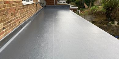 Newly installed flat grey roof on a brick building.