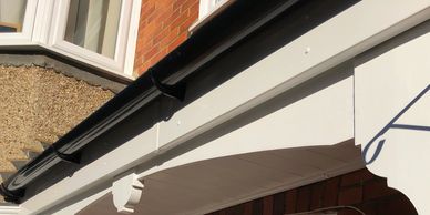 Close-up of a white fascia board and gutter on a brick house.