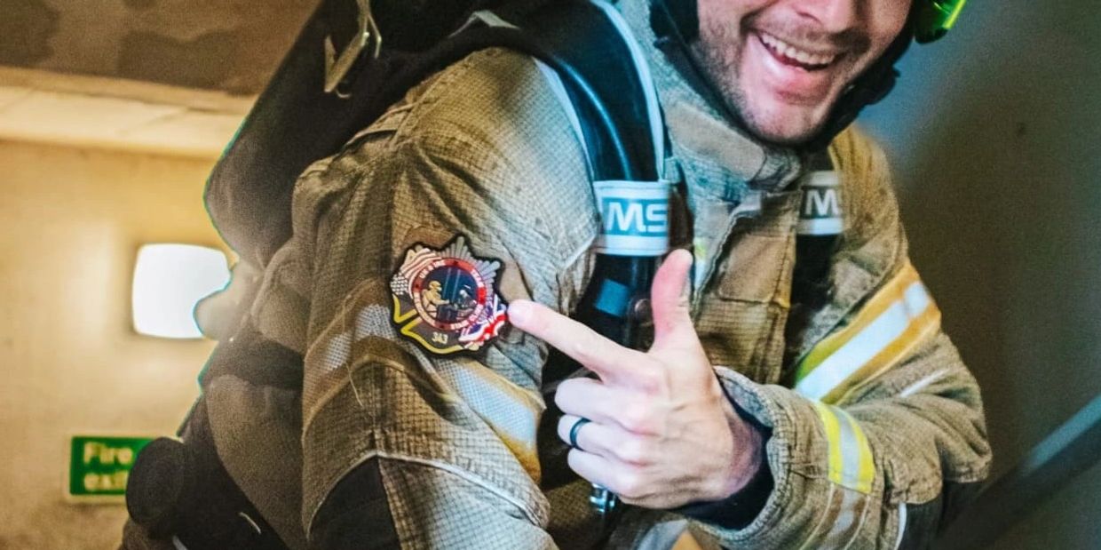 Firefighter pointing at a badge and smiling.