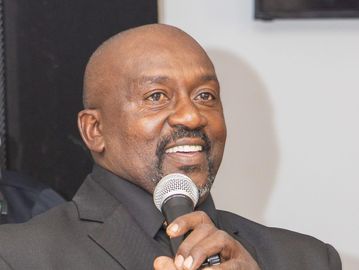 Man speaking into a microphone with a smile.