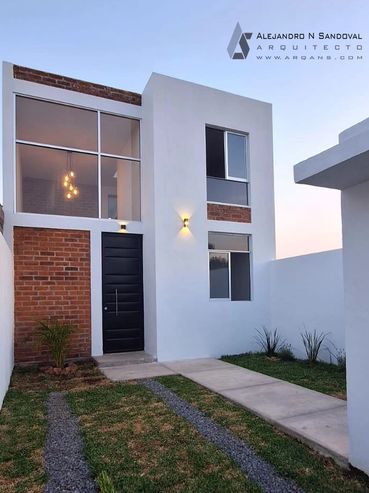Modern two-story house with brick and white exterior, featuring a black front door and garden path.