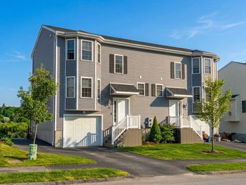 Modern two-story townhouse with garages and landscaped front yard.