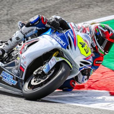 Motorcycle racer leaning into a sharp turn on track.