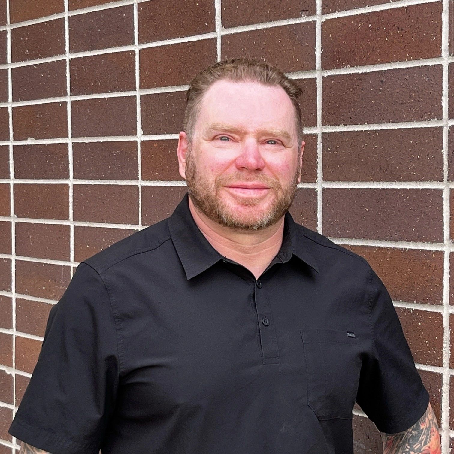 Shaun Free, keynote speaker, standing in front of a brick wall.