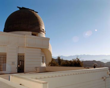 Observatory dome under clear sky with mountains.