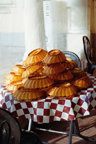 Stacked wicker lamp shades on a checkered table.