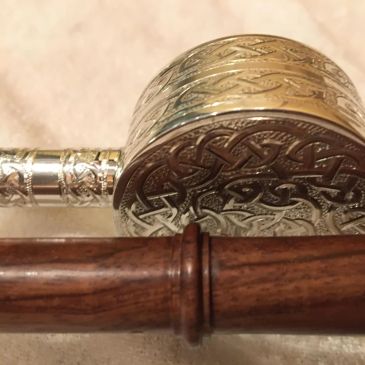Engraved metal component with a wooden handle.