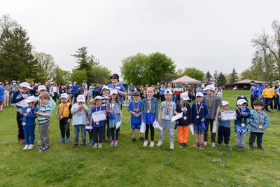 Children celebrating with medals and certificates outdoors.