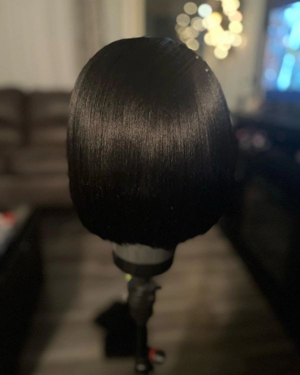 Shiny black bob wig on a stand.