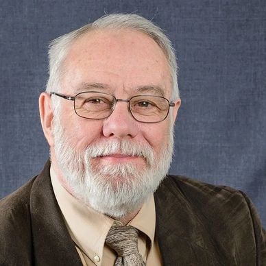 Portrait of a smiling elderly man with glasses and a beard.