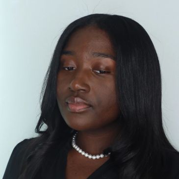 Portrait of a thoughtful young woman with long black hair and a pearl necklace.