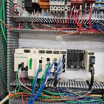 An organized electrical control panel with cables and Schneider Electric components.