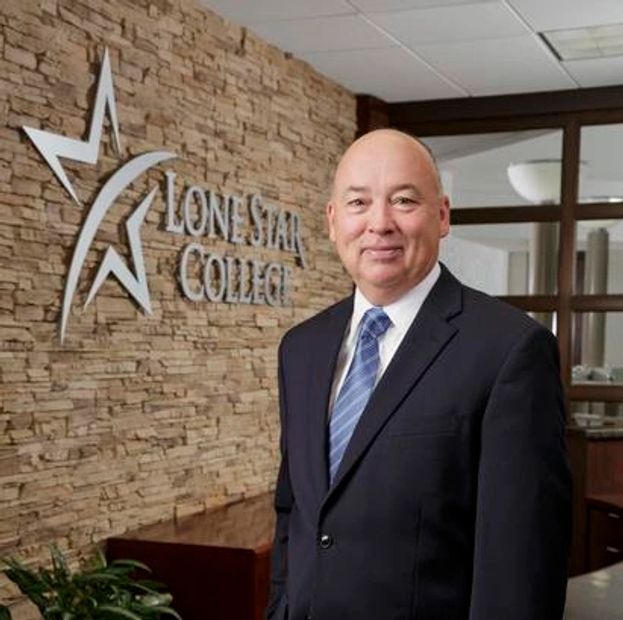 A man in a suit stands in front of a Lone Star College sign.