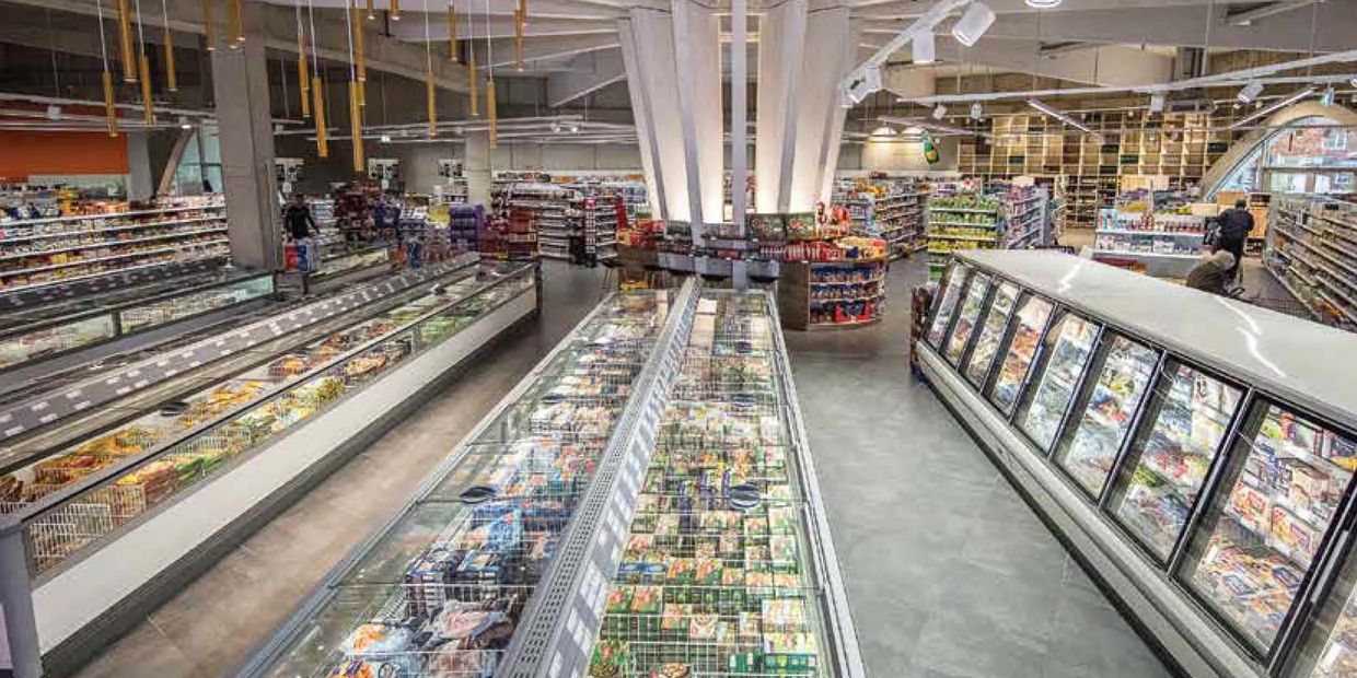 Modern supermarket aisle with frozen food freezers and well-lit shelves.
