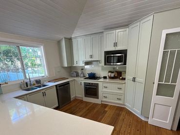 Bright kitchen with white cabinets, wooden floor, and modern appliances.