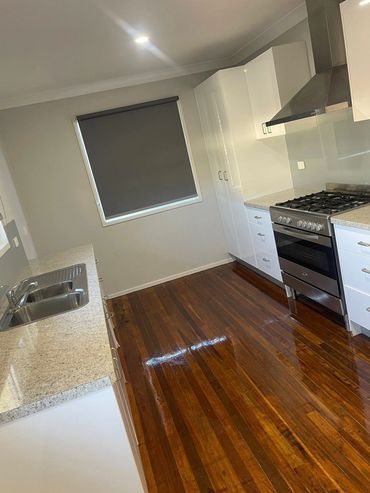Modern kitchen with polished wooden floors and white cabinetry.