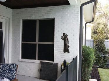 A white brick wall with a decorative figure and a large window.
