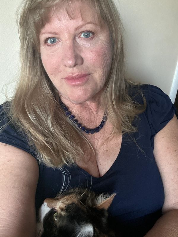 Woman with blue eyes holding a multi-colored cat in her arms.