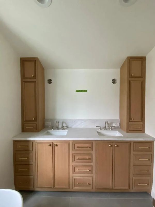 Double sink bathroom vanity with wooden cabinets and white countertop.
