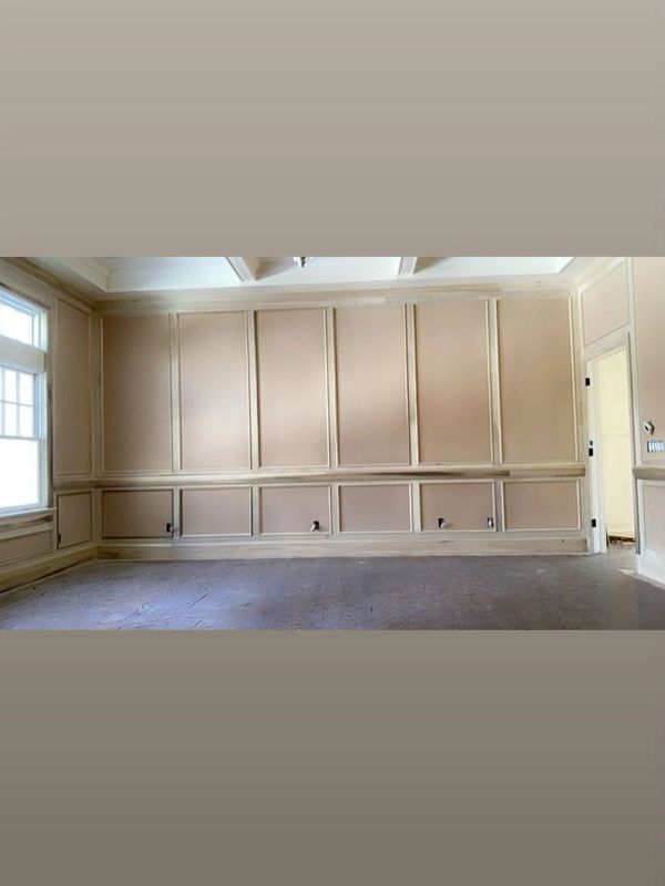Empty room with beige paneled walls and large windows letting in natural light.