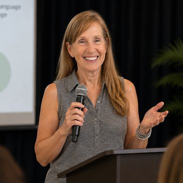 Woman speaking and smiling at a podium.