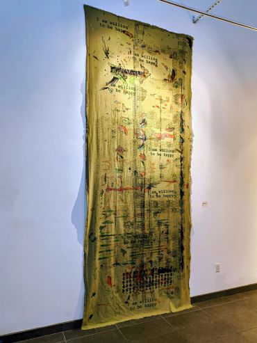 Text and images on a tall fabric hanging on a gallery wall.