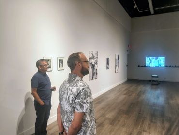 Two men observing artwork in a gallery.