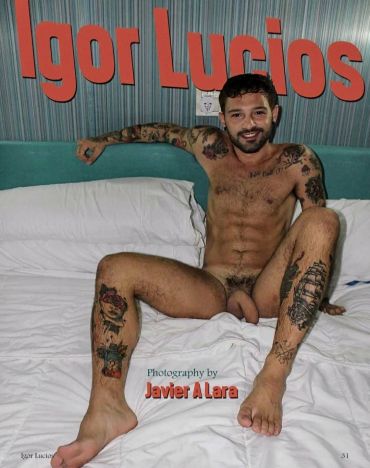 Man with tattoos posing nude on bed.