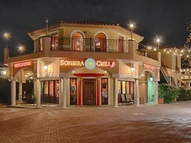 A warmly-lit, two-story restaurant named Sonrisa Grill at night