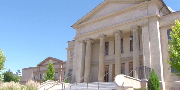 A grand classical building with tall columns and steps under a clear blue sky.