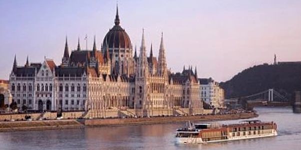 Majestic parliament building by a river with a boat passing.